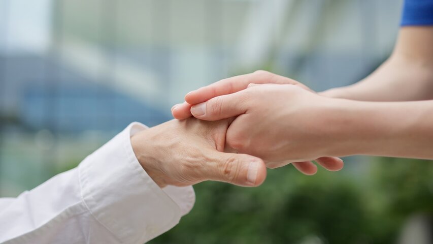 close up of nurse holding hand of resident