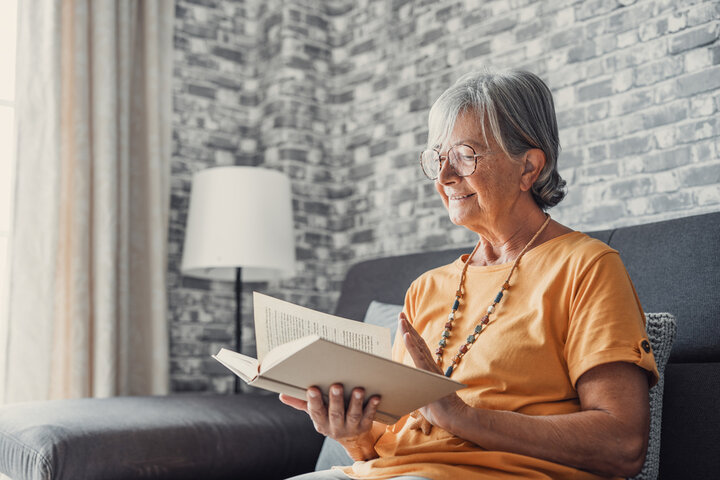 older woman relaxing a reading a book at a care home